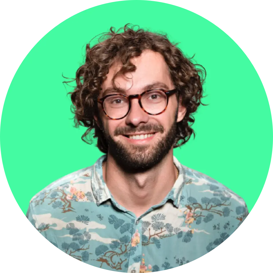 Man with curly brown hair wearing a blue floral shirt, standing against a bright green circular background, presenting a friendly and approachable atmosphere